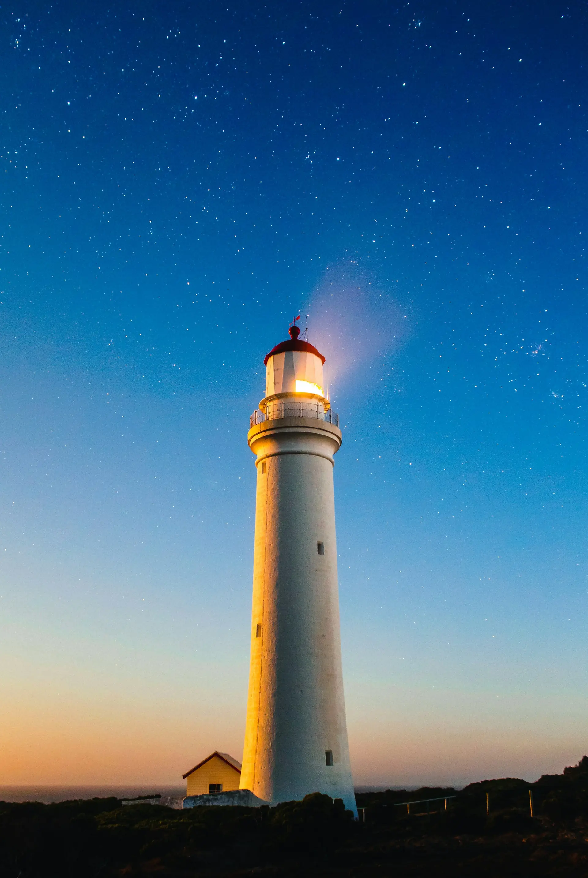 Un phare blanc illuminé au crépuscule